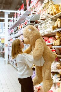 woman carrying bear plush toy inside store