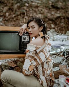 woman wearing white and brown shirt beside tv
