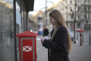 woman in black coat standing beside red telephone booth