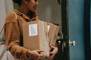 ethnic woman entering house with cardboard boxes