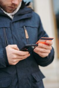 anonymous guy with plastic card making online payment using smartphone on street