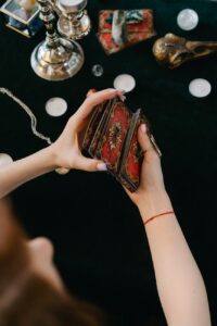anonymous female fortune teller shuffling tarot cards at table