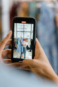 person taking a video of woman holding a blue dress