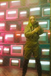 woman in green jacket standing beside chain link fencee