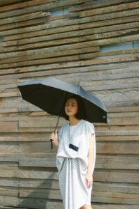 woman in white and black stripe long sleeve shirt holding umbrella
