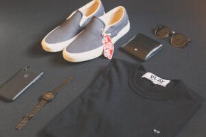 pair of gray vans low top sneakers beside black shirt sunglasses and watch