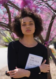 woman standing beside tree holding book
