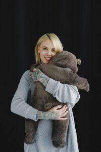 happy mother hugging baby in bear costume in photo studio