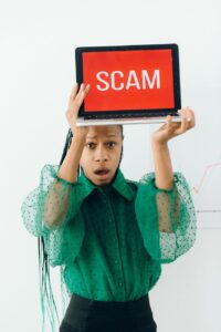 woman holding a laptop with a scam text