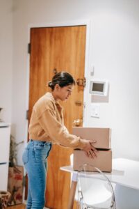 young ethnic woman packing carton boxes