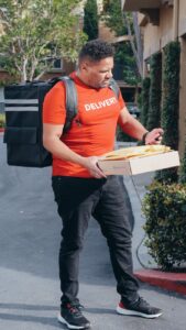 a deliveryman carrying a package and mails looking for the address