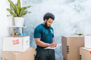 a man in blue shirt writing on a clipboard near parcels