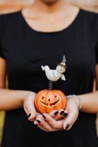 person holding a toy jack o lantern with a ghost